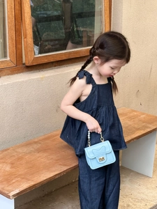 Detail of light blue girls handbag with heart pattern and pearl handle on denim outfit