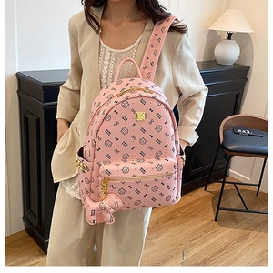 Detail showing pink faux leather backpack with cat print and gold zipper on a model