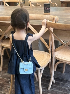 Detail of light blue mini bag with pearl handle and golden chain on a child