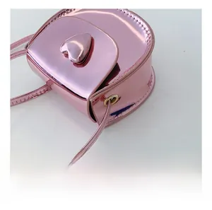 Close-up of pink heart-shaped crossbody bag with glossy finish and metal eyelet detail