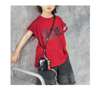 Detailed view of kids red t-shirt paired with distressed denim shorts and a black neck bag