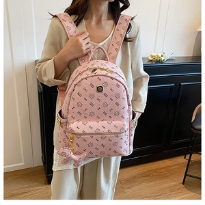 Detailed close-up of pink PU leather backpack with cat print and puppy pendant