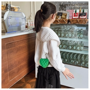 Détail du mini sac vert en forme de cœur avec chaîne sur une fille élégante
