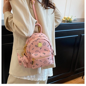 Detailed view of pink mini backpack featuring cat prints and a golden logo plate on the front
