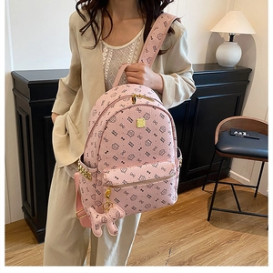 Detail of pink fashion backpack with cute dog charm and metallic gold zippers on bag