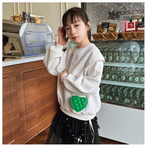 Détail d'un mini sac à chaîne matelassé vert vif en forme de cœur pour enfant avec tenue