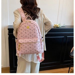 Detail of pink fashion backpack with all-over print and gold zippers on model's back