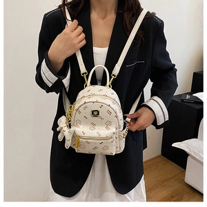 Mini white backpack with cute cat prints and bow charm shown on model in modern interior