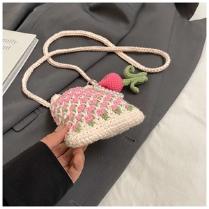 Détail d'un sac bandoulière au crochet avec fleurs roses, perles et fraise