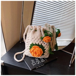 Detail einer handgehäkelten Beuteltasche mit orangefarbenen Blumen auf Buch