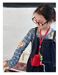 Close-up of red leather mini neck bag with colorful beads and embossed Melter text