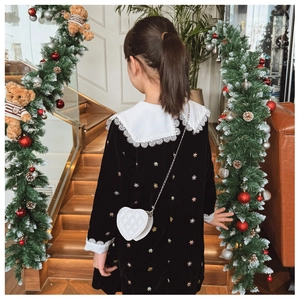 Gros plan d'un sac cœur blanc matelassé avec chaîne sur une robe de fille en velours noir