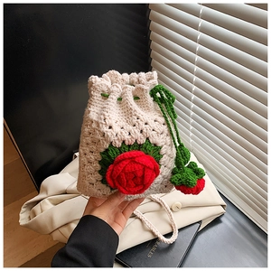 Nahaufnahme einer handgehäkelten Tasche mit roter Rose und weißem Strickmuster