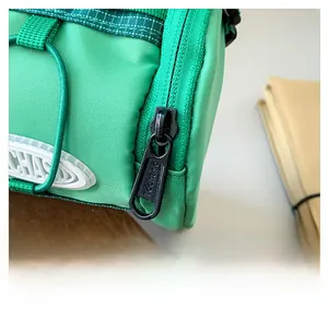 Gros plan de la fermeture éclair fluide et du nylon vert du sac bandoulière pour enfant