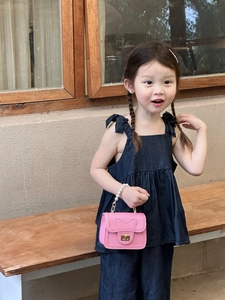 Detail of pink mini kids handbag featuring a pearl handle and gold heart lock buckle