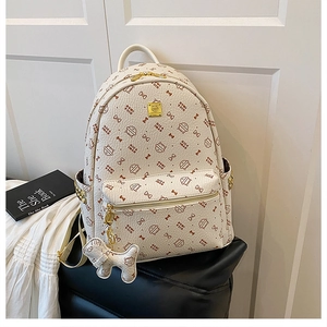 Close-up of beige leather backpack with cat print, gold studs, and matching dog charm