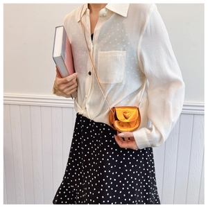 Close-up of mini orange heart-shaped crossbody bag with metallic finish and strap