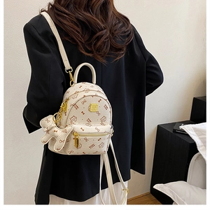 Detail of cream mini backpack with cat print and bear charm on a model's shoulder