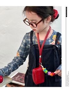 Detail of red mini neck bag for kids with embossed letters and colorful bead strap
