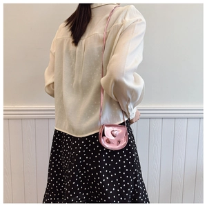 Rear view of a child wearing a shiny pink heart-shaped mini crossbody bag with chain strap