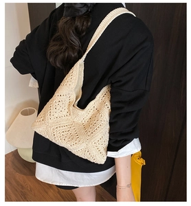 Rear view of a beige hand-crocheted hollow shoulder bag worn in a cozy indoor setting