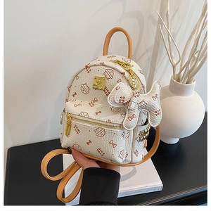 Detail of a mini cream cat-pattern backpack with a cute dog pendant and golden studs