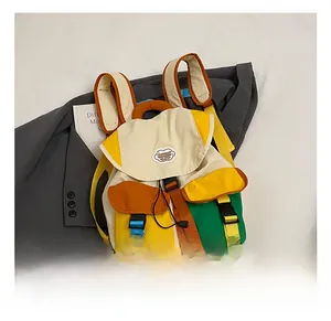 Detail of color-block school backpack with buckle closures on a grey blazer backdrop