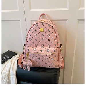Close-up of pink cat print backpack on a black chair with books in a lifestyle setting