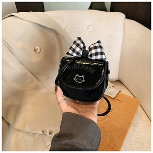 Detailed view of mini black glossy crossbody bag with plaid bow and cat charm
