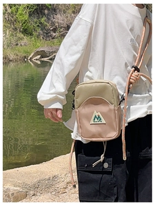Détail du mini sac bandoulière outdoor avec logo montagne et bandoulière en corde orange