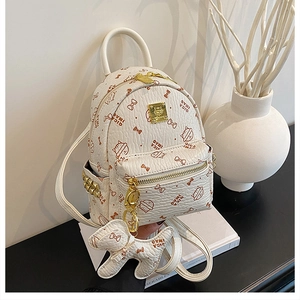 Detail of white faux leather mini backpack featuring cartoon cat prints and gold hardware