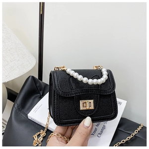 Detail view of mini black pearl handle bag with gold twist lock and lychee texture