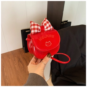 Close-up of red mini cat shoulder bag with plaid bow and glossy patent leather finish