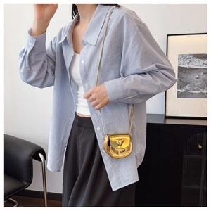 Close-up of a mini gold heart-shaped crossbody bag with a slim metallic chain strap
