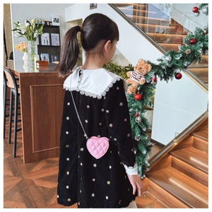 Détail du sac bandoulière rose en forme de cœur sur une robe en velours noir à fleurs
