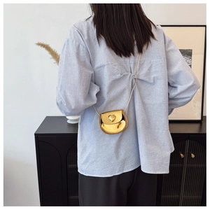 Detail of a mini golden heart-shaped metallic bag featuring a sleek mirror finish surface
