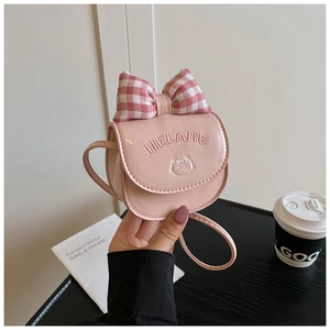 Detail of pink faux leather crossbody bag featuring a plaid bow and cat embroidery