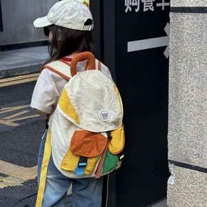 Kids color-block backpack with cloud patch shown on a child model in an urban street setting