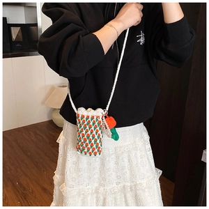 Détail d'un sac à téléphone crocheté main avec motif tulipe et breloque carotte