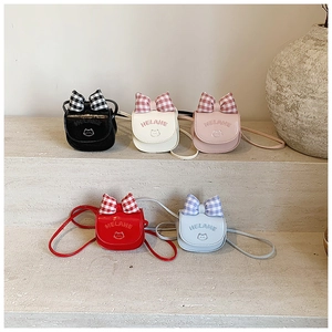 Detail of cute cat shoulder bags in five colors with plaid bows on stone steps