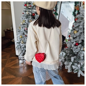 Gros plan d'un sac à bandoulière cœur rouge matelassé avec bordure en perles pour enfant