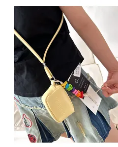 Close-up of a yellow mini neck bag for kids featuring a colorful letter bead keychain