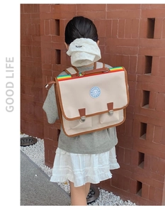 Détail du sac à dos vintage avec poignée arc-en-ciel et finitions en cuir brun