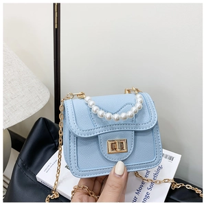 Detail of light blue pearl handle mini bag with lychee texture and gold chain strap