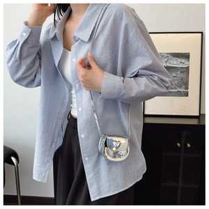 Girl's silver heart-shaped mini crossbody bag with chain strap shown on a model