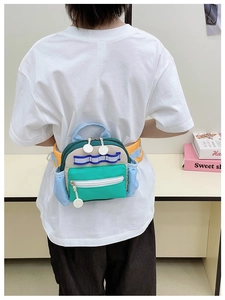 Detail der bunten Nylon-Kindertasche mit mehreren Taschen und verstellbarem Gurt am Model