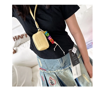 Detailed view of yellow mini neck pouch with embossed letters and colorful charm