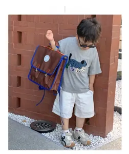 Garçon portant un sac à dos vintage en toile marron et bleu avec un t-shirt gris à motif chien