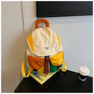 Detail of multi-color canvas backpack with cloud patch and buckle pocket features