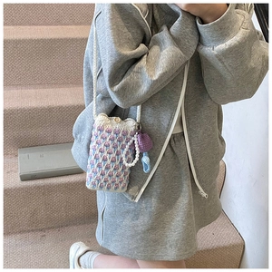 Détail d'un sac à bandoulière en tricot fait main avec chaîne de perles et cœur rose